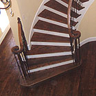 Curved wood staircase with a wood newel and iron balusters
