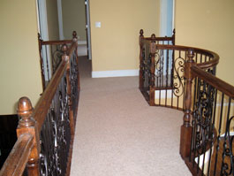 Second level landing with wood handrail and iron balusters